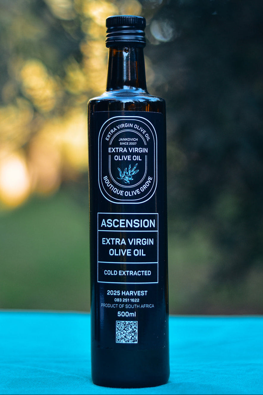 Bottle of Ascension Extra Virgin Olive Oil on a blue surface with a blurred natural background